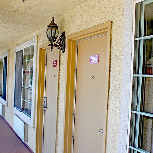 The image shows a hotel or motel corridor with beige doors and windows. Doors are numbered 101 and 104, with wall-mounted lamps beside them.