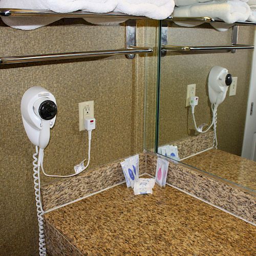 The image shows a bathroom vanity with a mirror, hairdryer, towels on a rack, and toiletries on a granite countertop, ending the sentence.