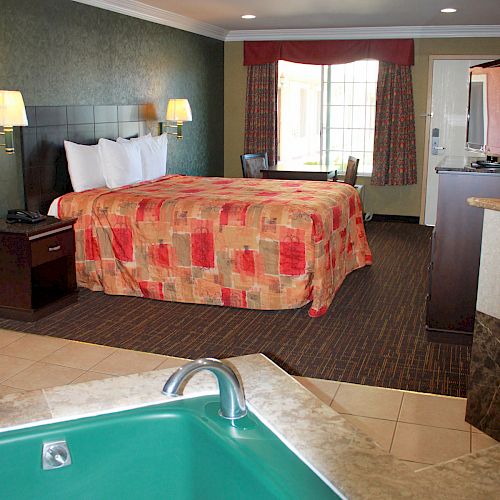 The image shows a hotel room with a large bed, two bedside lamps, a window with curtains, and a green jacuzzi at the forefront.