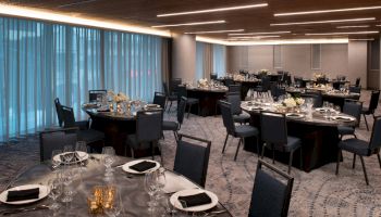 The image shows an elegant banquet room set up with round tables, chairs, and place settings, ready for an event or dinner.